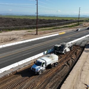 A white-water truck on leveled dirt next to the road.