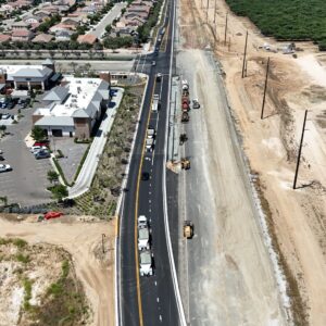 A straight road with a shopping center on the left and construction equipment on the right.