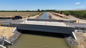 A horizontal view of the bridge with orange cones placed alongside the bridge barrier rails.
