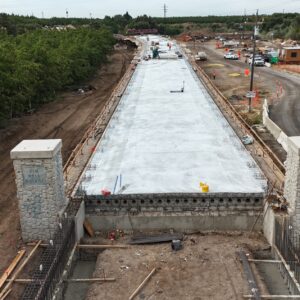 Start of Tim Bell bridge with a construction area before and concrete after two set stone columns.