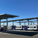 Line of trucks lined up getting charged under solar panels.